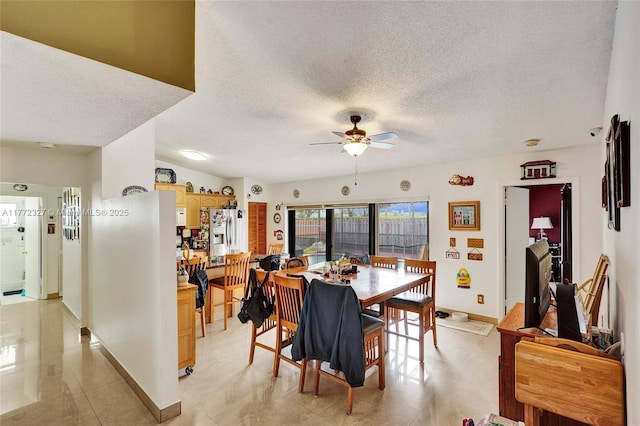 dining area with baseboards, a ceiling fan, and a textured ceiling