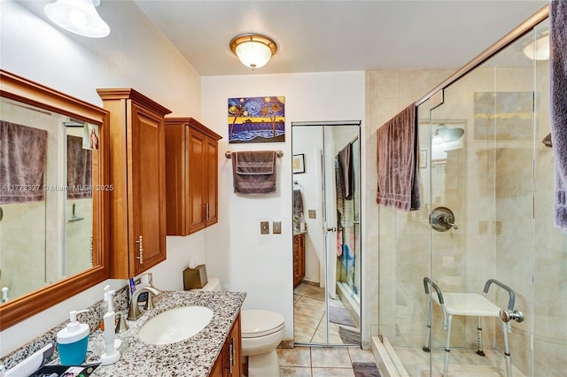 bathroom with tile patterned floors, vanity, a shower stall, and toilet
