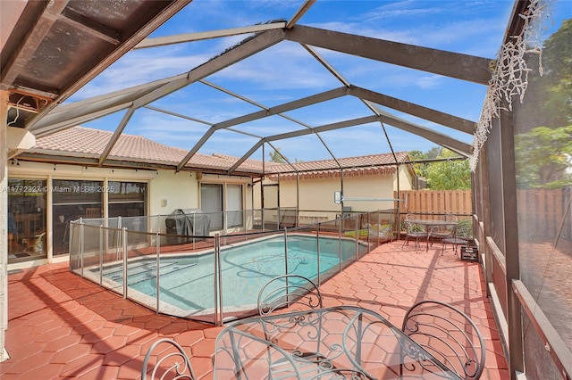 view of swimming pool featuring glass enclosure, fence, a patio, and a fenced in pool