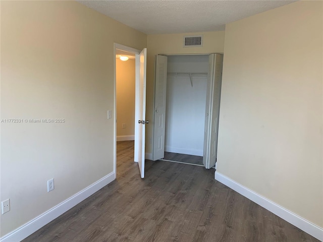 unfurnished bedroom with dark wood-style flooring, baseboards, and a closet