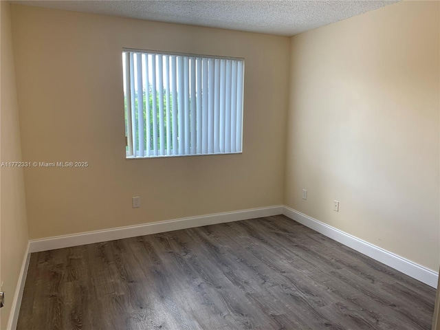 spare room featuring wood finished floors, a textured ceiling, and baseboards