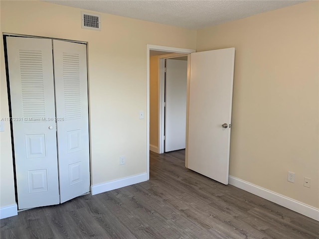 unfurnished bedroom featuring dark wood finished floors, a closet, and baseboards