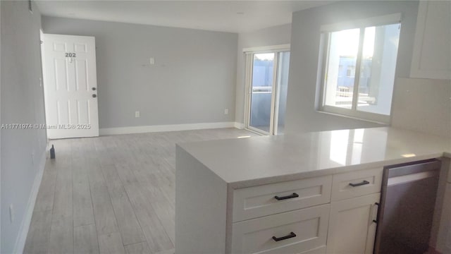kitchen with light countertops, baseboards, white cabinetry, light wood-type flooring, and open floor plan