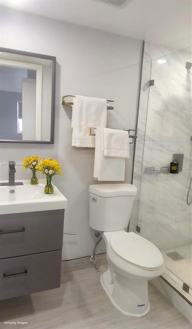 full bath featuring toilet, vanity, and a marble finish shower