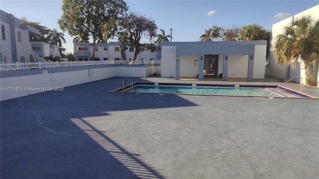 community pool with a patio area and fence