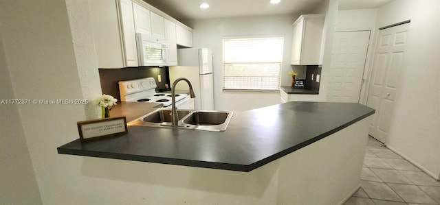 kitchen featuring white appliances, dark countertops, white cabinets, and a peninsula