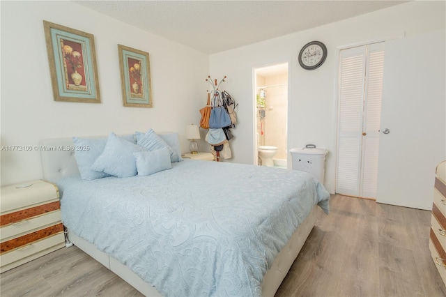 bedroom featuring a closet, ensuite bath, and wood finished floors