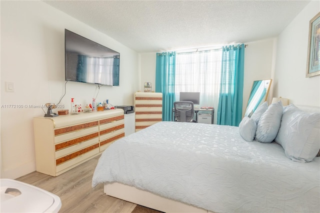bedroom featuring light wood finished floors and a textured ceiling