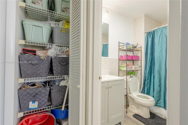 bathroom featuring tile walls, toilet, vanity, and wood finished floors