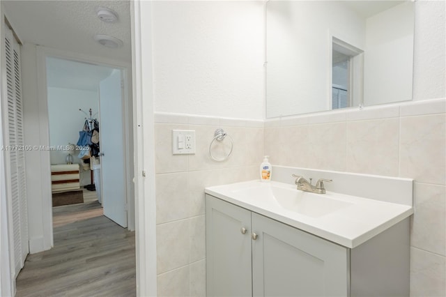 bathroom with vanity, tile walls, a textured ceiling, a wainscoted wall, and wood finished floors
