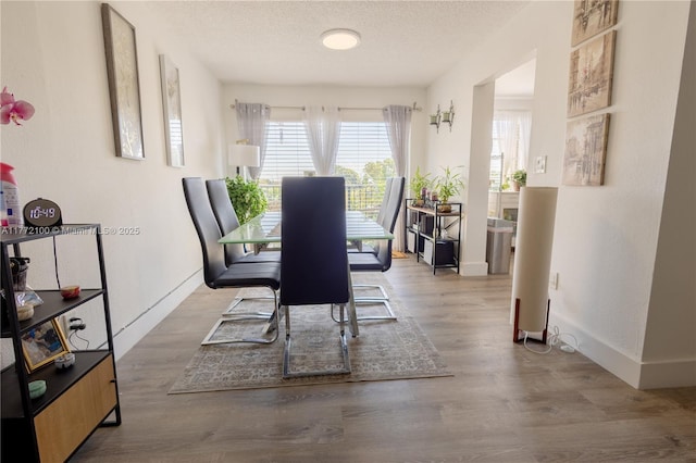 dining space featuring wood finished floors, baseboards, and a textured ceiling