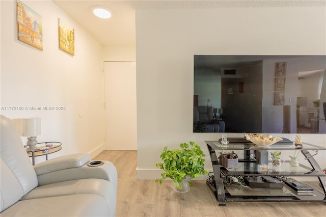 living area featuring baseboards, visible vents, and wood finished floors