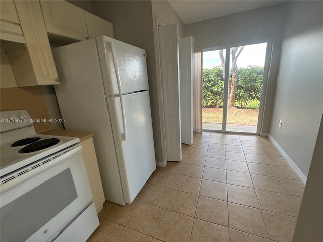 kitchen featuring baseboards, light tile patterned floors, and white appliances