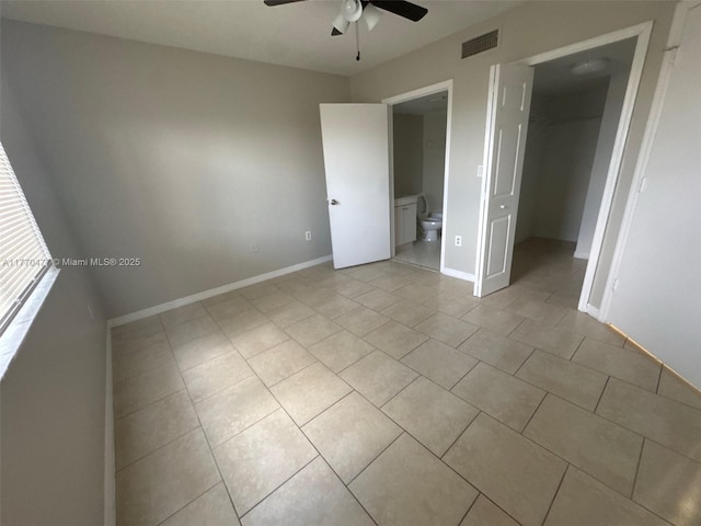 unfurnished bedroom with a walk in closet, light tile patterned floors, baseboards, visible vents, and ensuite bathroom