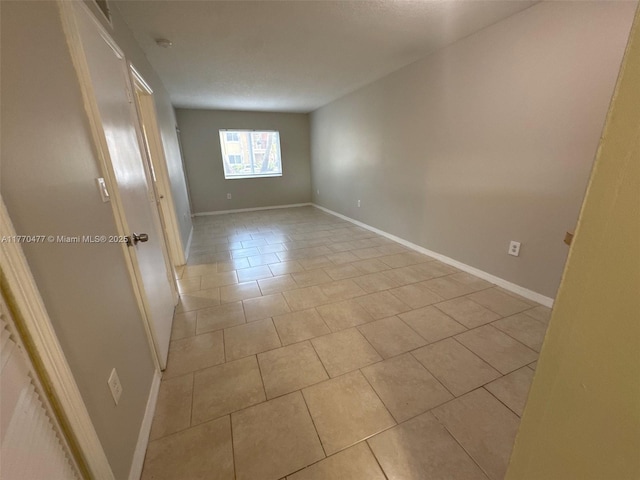 unfurnished room with light tile patterned flooring and baseboards