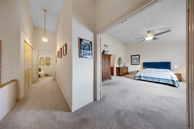 bedroom with baseboards, a high ceiling, light carpet, and a ceiling fan