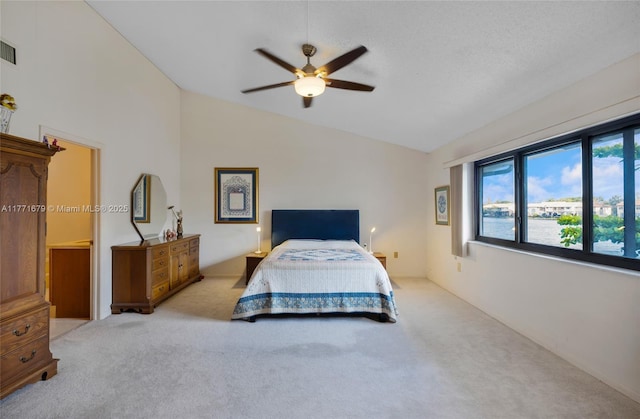 carpeted bedroom with ceiling fan, visible vents, and lofted ceiling