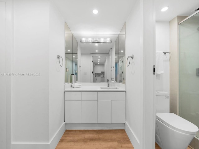2301 Collins Ave Unit 603, Miami Beach, FL 33139 - bathroom featuring vanity, toilet, a stall shower, recessed lighting, and wood finished floors