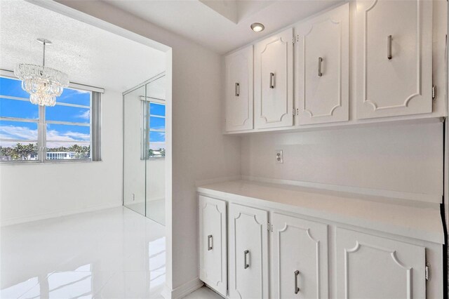 3113 S Ocean Dr Unit 410, Hallandale Beach, FL 33009 - interior space with a notable chandelier, light countertops, white cabinetry, baseboards, and decorative light fixtures