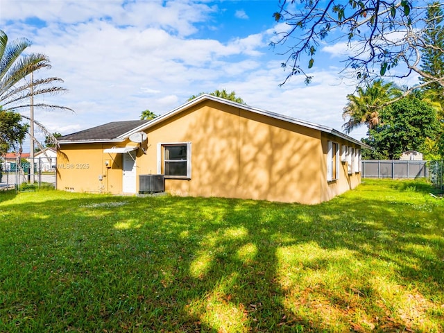 back of house featuring a yard, central AC unit, stucco siding, and fence