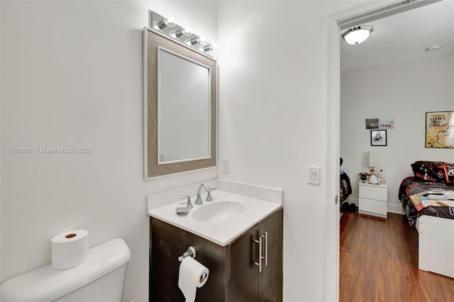 half bathroom featuring toilet, wood finished floors, and vanity