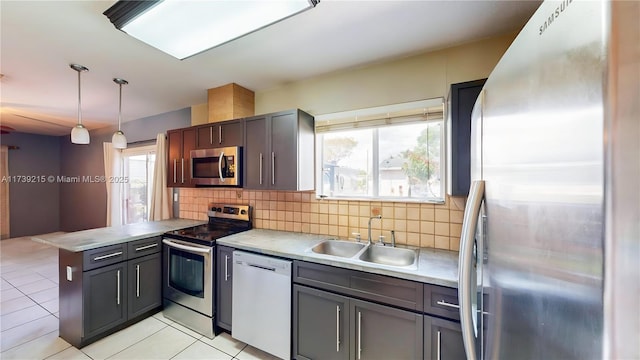 kitchen with a peninsula, a sink, backsplash, and appliances with stainless steel finishes