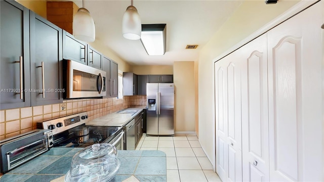 kitchen featuring tasteful backsplash, appliances with stainless steel finishes, visible vents, gray cabinetry, and light tile patterned flooring