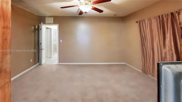 empty room with carpet, visible vents, a ceiling fan, and baseboards