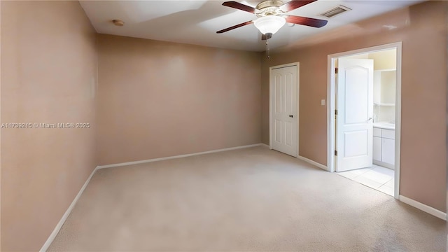 spare room with light colored carpet, baseboards, a ceiling fan, and visible vents