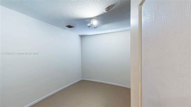 unfurnished room with baseboards, visible vents, and a textured ceiling