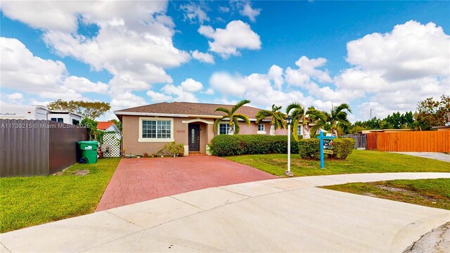 view of front of property with fence, a front lawn, stucco siding, and driveway