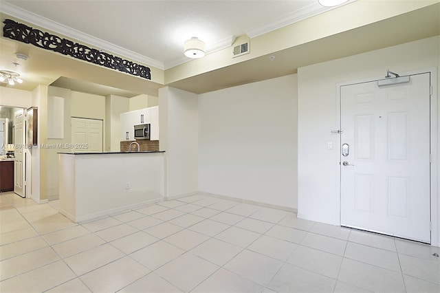 empty room with ornamental molding, light tile patterned floors, and baseboards