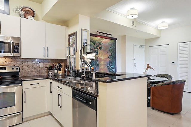 kitchen with stainless steel appliances, light tile patterned flooring, a peninsula, ornamental molding, and dark stone countertops