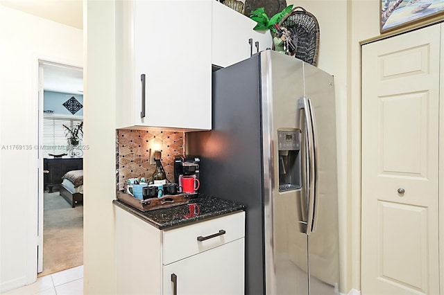 kitchen with stainless steel fridge, tasteful backsplash, white cabinets, and light tile patterned floors