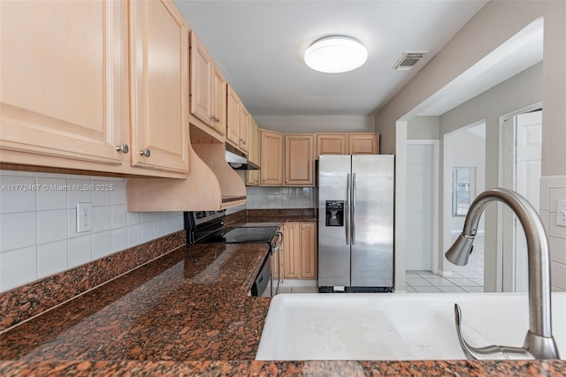 kitchen with light brown cabinetry, stainless steel fridge, range with electric stovetop, under cabinet range hood, and visible vents