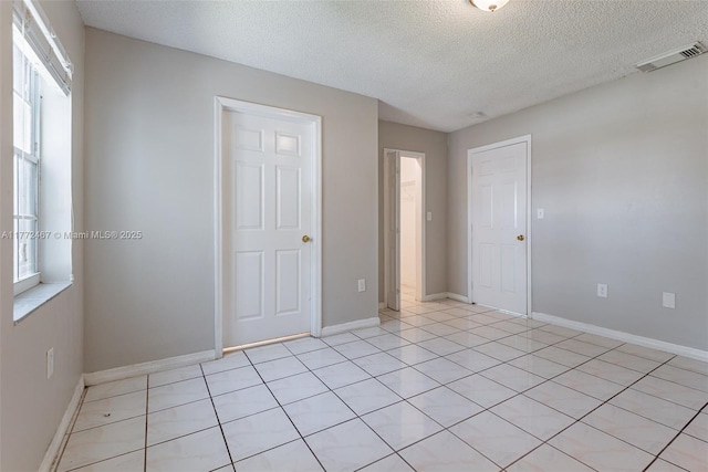 unfurnished room with a textured ceiling, baseboards, and visible vents