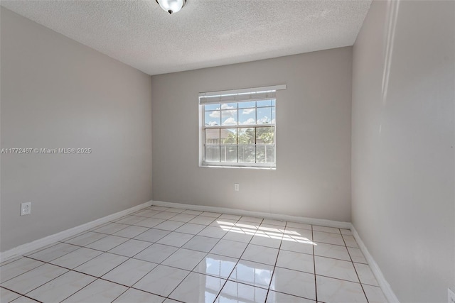 unfurnished room featuring light tile patterned floors, baseboards, and a textured ceiling