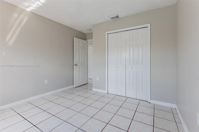 unfurnished bedroom featuring a closet, baseboards, a textured ceiling, and visible vents