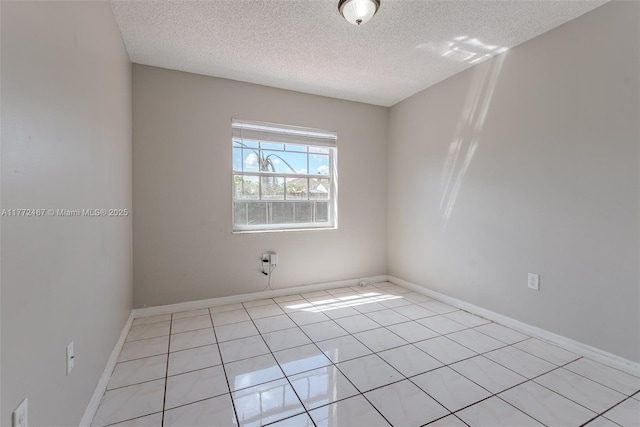 spare room featuring baseboards, a textured ceiling, and light tile patterned flooring