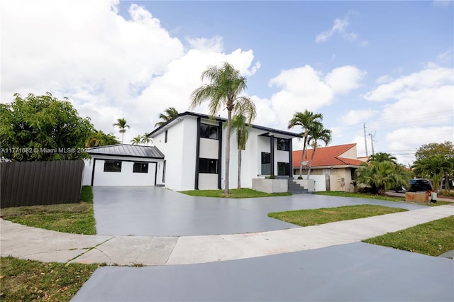 view of front of home with stucco siding, an outdoor structure, a standing seam roof, and concrete driveway