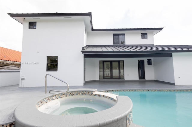 back of house featuring a standing seam roof, metal roof, french doors, a pool with connected hot tub, and a patio area