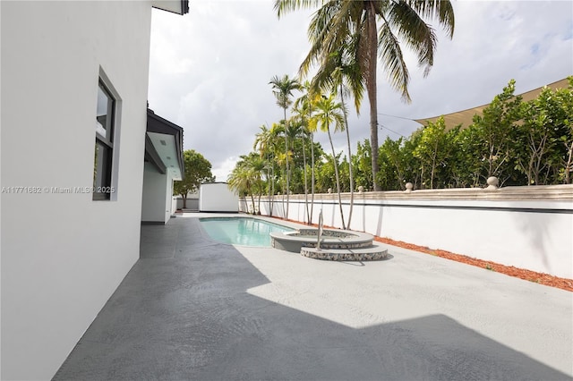view of pool with fence, a pool with connected hot tub, and a patio area