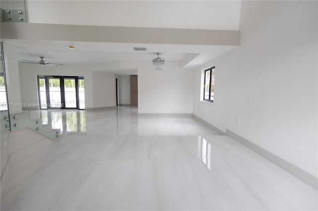 empty room with baseboards, visible vents, a healthy amount of sunlight, and a ceiling fan