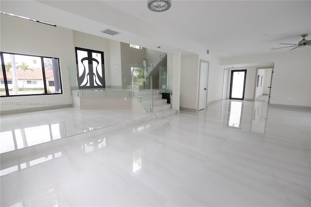 unfurnished room with baseboards, visible vents, ceiling fan, and stairway