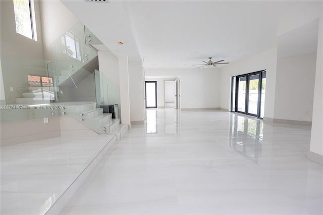 interior space with baseboards, stairway, and a ceiling fan