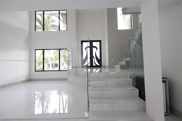 stairs with a towering ceiling and a healthy amount of sunlight