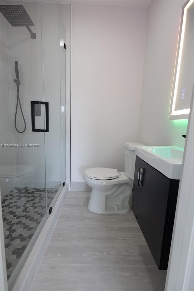 full bathroom featuring a shower stall, wood finished floors, toilet, and vanity