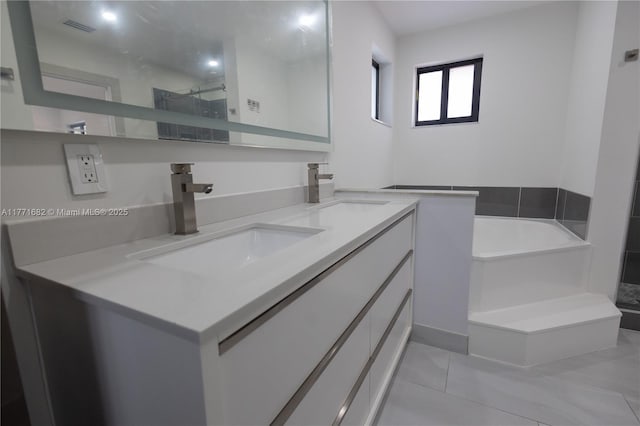 bathroom featuring double vanity, a sink, a bath, and visible vents