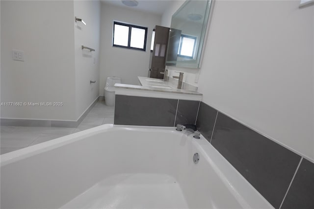 full bathroom featuring baseboards, toilet, vanity, and a bathtub