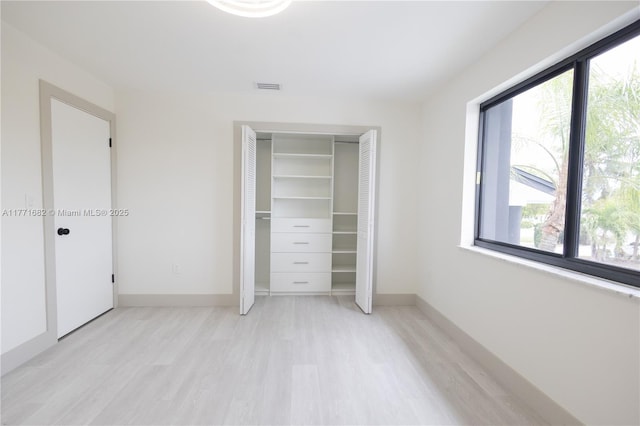 unfurnished bedroom with light wood finished floors, baseboards, visible vents, and a closet